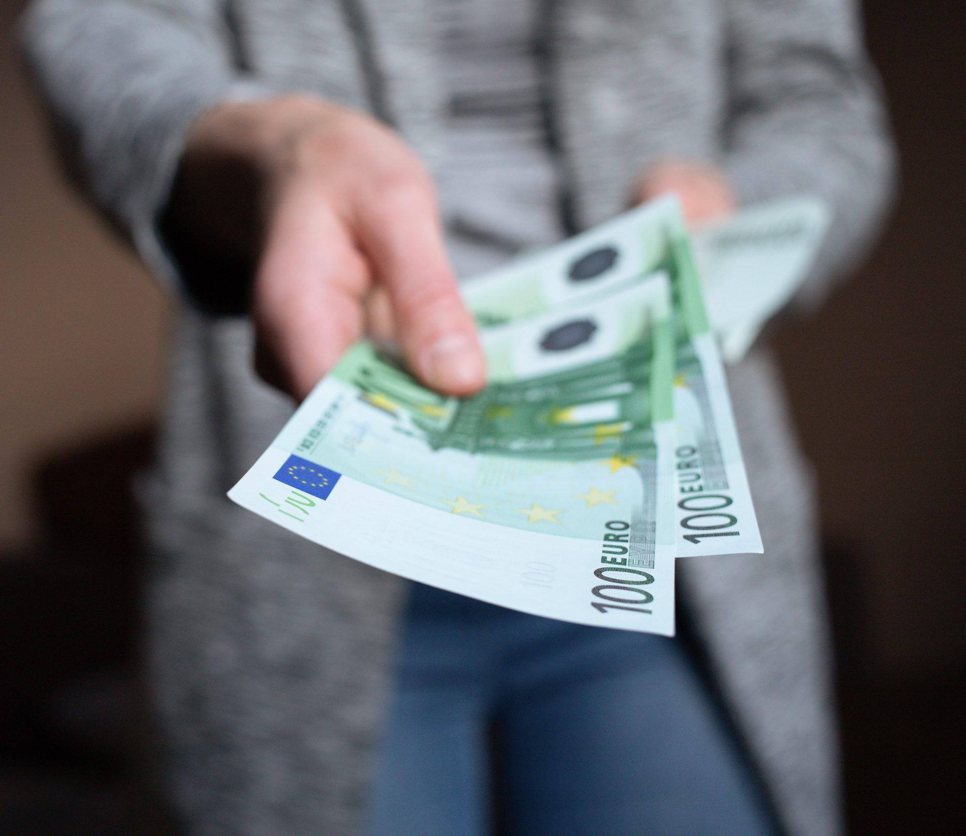 Kambodżańskie banknoty, kalkulator, okulary i długopis na stole.